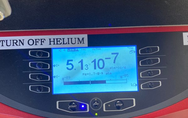 Helium leak detector with leak rate displayed on the screen.